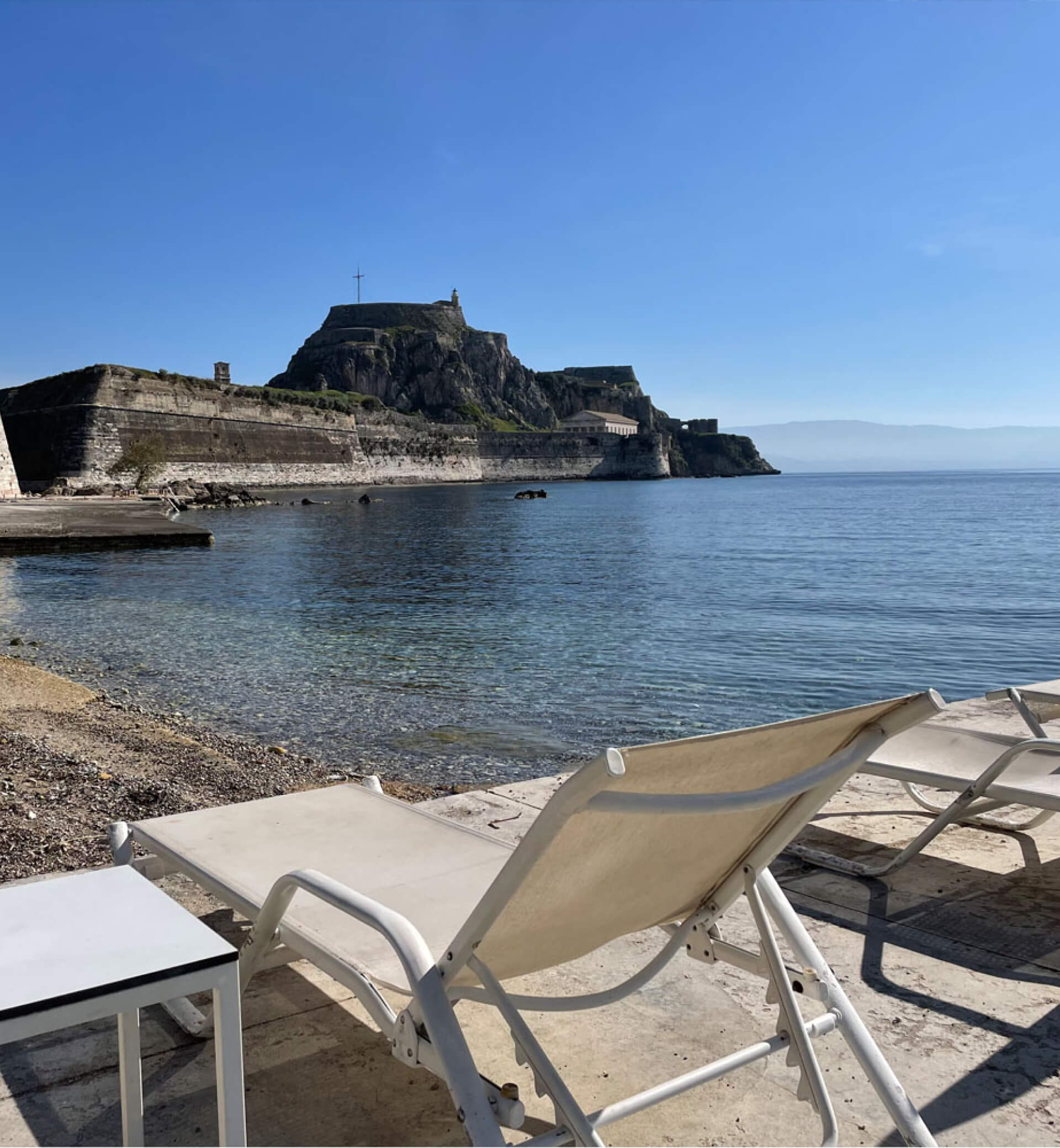 Picturesque beach in front of Azur, with sunbeds and the enchanting old fortress in the background