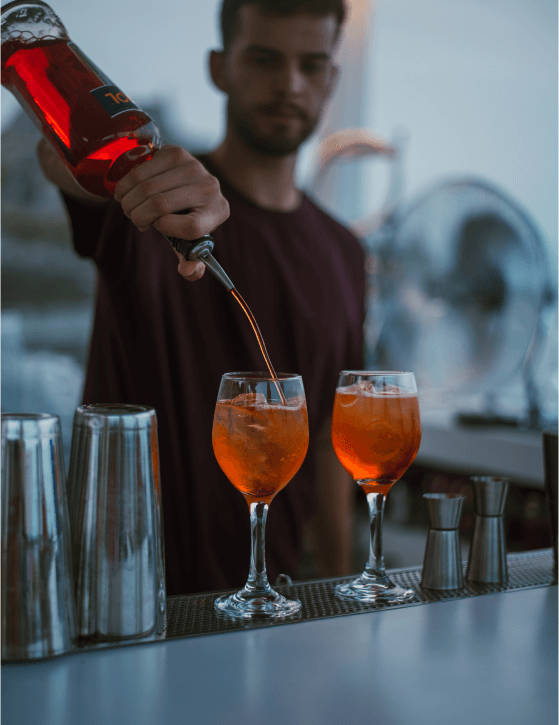 Skillful bartender pouring refreshing Aperol Spritzes with precision and style